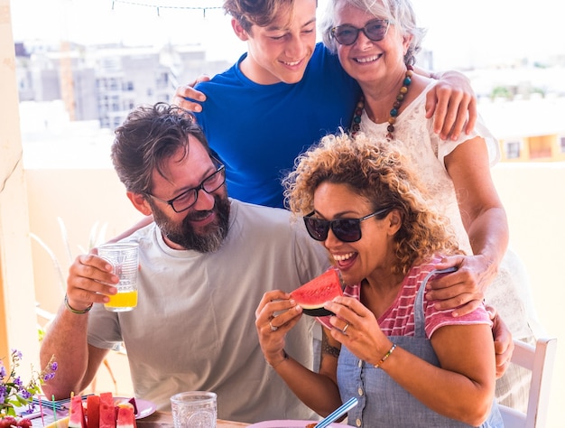 Famiglia multigenerazionale felice e sorridente che si gode cibo e bevande insieme