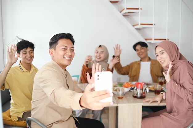 Famiglia musulmana asiatica che cena l'iftar e fa videoconferenze mentre mangia cibo tradizionale durante R