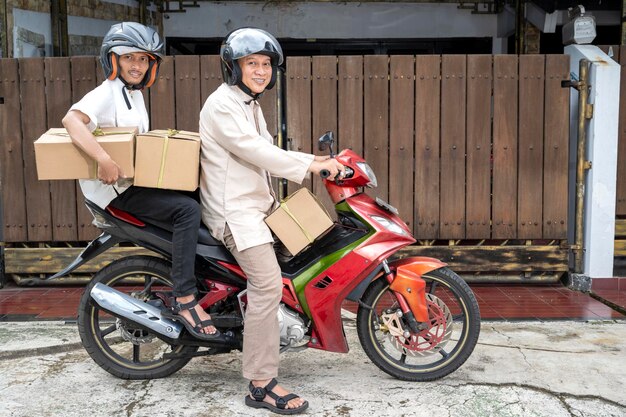 Famiglia musulmana asiatica che porta una scatola sulla motocicletta pronta per andare mudik