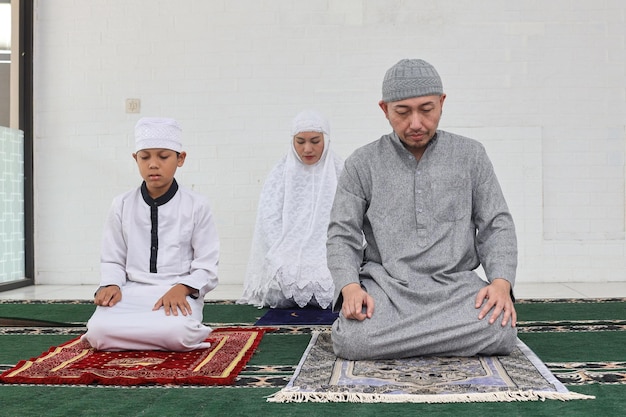 Famiglia musulmana asiatica che prega salah jamaah insieme a casa ultimo movimento sulla procedura salat