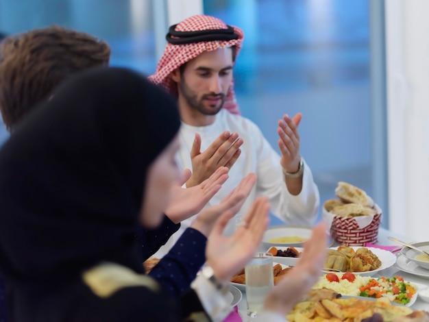 Famiglia musulmana che fa iftar dua per rompere il digiuno durante il Ramadan. Popolo arabo che tiene le mani in gesto per pregare e ringraziare Allah prima della cena tradizionale