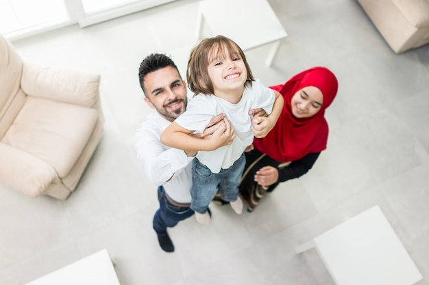 Famiglia musulmana felice a casa moderna divertendosi e buon tempo insieme