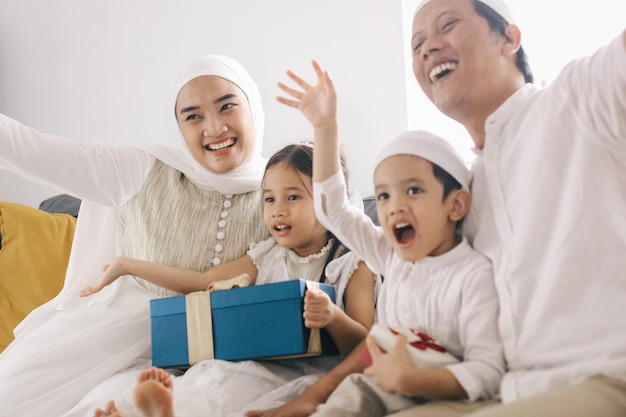 Famiglia musulmana felice che celebra il momento di Eid Mubarak con regali a casa