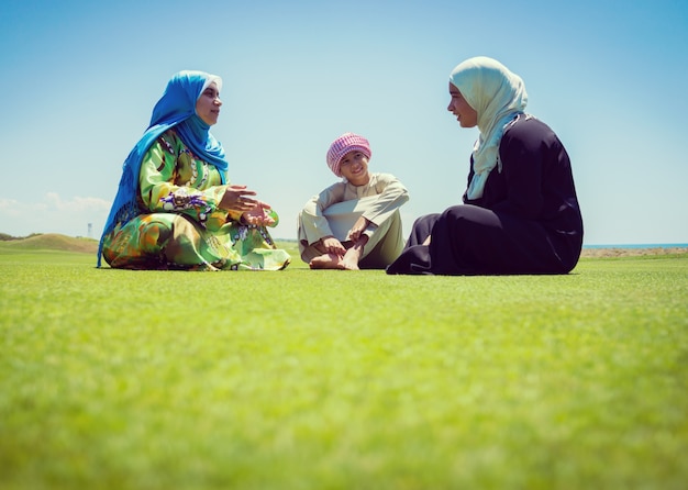 Famiglia musulmana felice sul prato verde