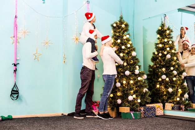 famiglia, natale, natale, inverno, felicità e concetto di persone - famiglia sorridente in cappelli di santa helper con molte scatole regalo e luci bengala