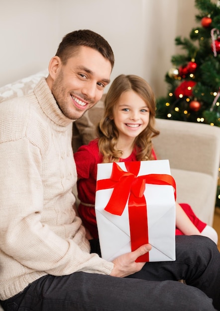 famiglia, natale, natale, inverno, felicità e concetto di persone - padre e figlia sorridenti che tengono scatola regalo