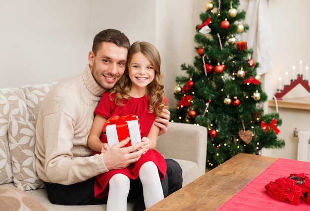 famiglia, natale, natale, inverno, felicità e concetto di persone - padre e figlia sorridenti che tengono scatola regalo