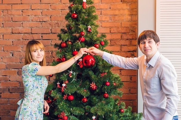 famiglia, natale, vacanze invernali e concetto di persone - coppia felice che decora l'albero di Natale a casa