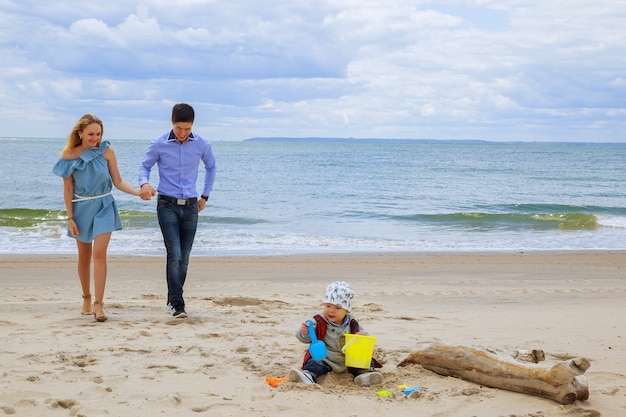 Famiglia radiosa in spiaggia genitori con figlio che gioca sulla spiaggia