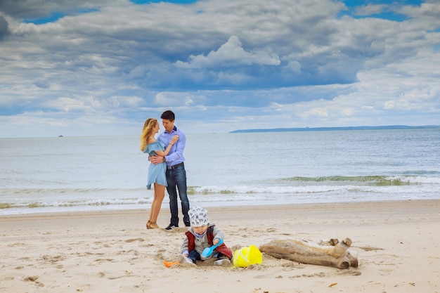 Famiglia radiosa in spiaggia genitori con figlio che gioca sulla spiaggia