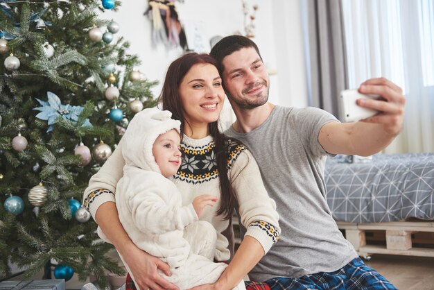 Famiglia riunita attorno a un albero di Natale, usando un tablet