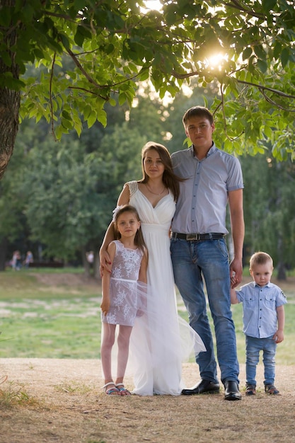 Famiglia sana in posa nel parco verde padre mamma figlia e ragazzino teleobiettivo