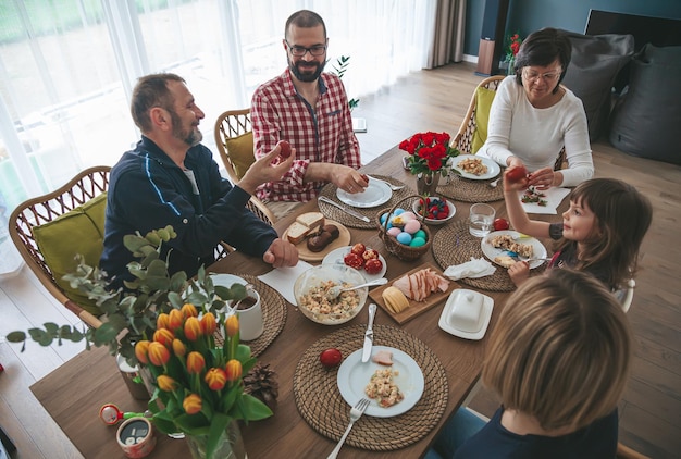 Famiglia schietta che si riunisce a casa per festeggiare e consumare la colazione di Pasqua