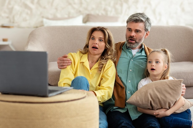 Famiglia scioccata che guarda film online sul laptop seduto a casa