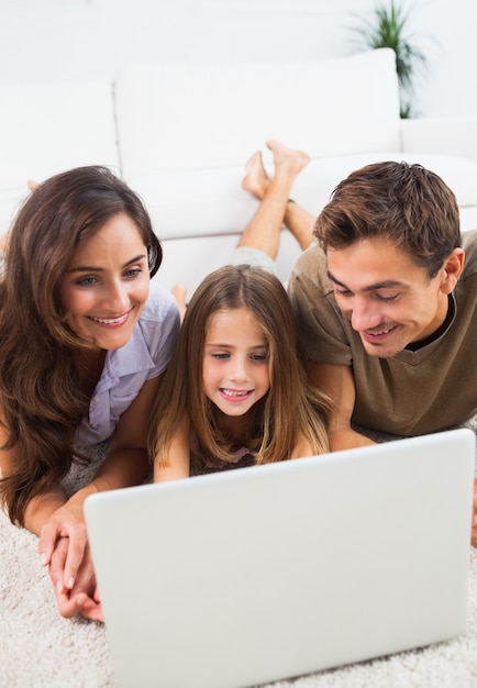 Famiglia sdraiata su un tappeto con il portatile