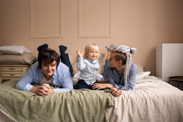 Famiglia sdraiata sul letto. Madre, padre e figlio che si divertono in camera da letto. Persone che si rilassano a casa.