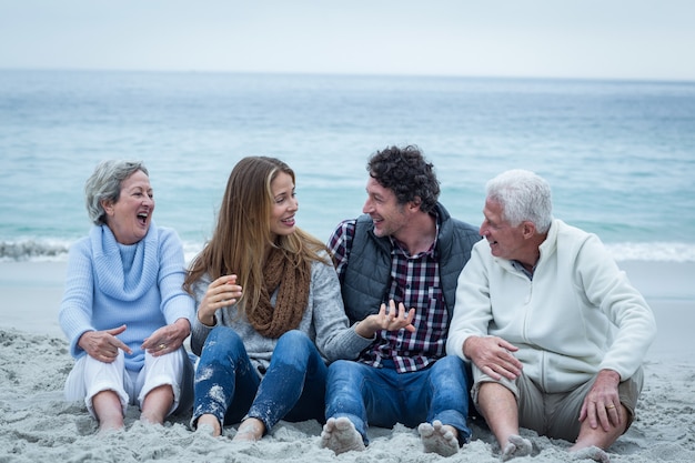 Famiglia sorridente che si siede alla riva di mare