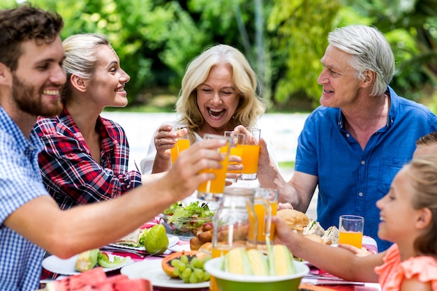 Famiglia sorridente che tosta succo al tavolo