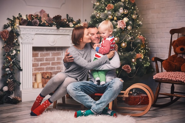 Famiglia sorridente felice all'interno di una casa sullo sfondo dell'albero di Natale con regali