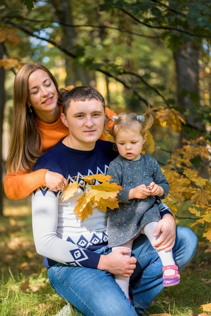 Famiglia sorridente felice che si distende nella sosta di autunno