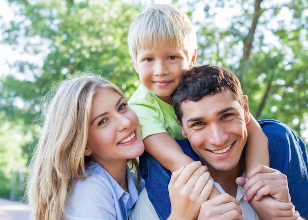 Famiglia sorridente felice con il figlio sullo sfondo del parco