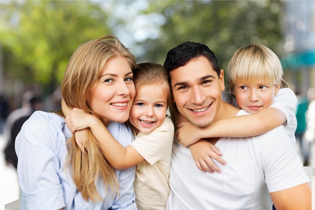 Famiglia sorridente felice con la figlia sopra il fondo degli alberi verdi