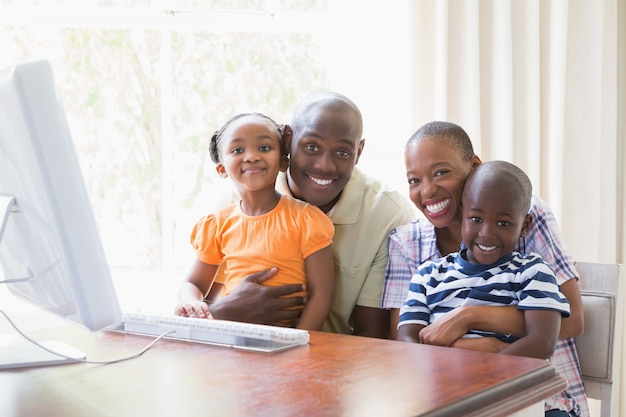 Famiglia sorridente felice del ritratto che per mezzo del computer