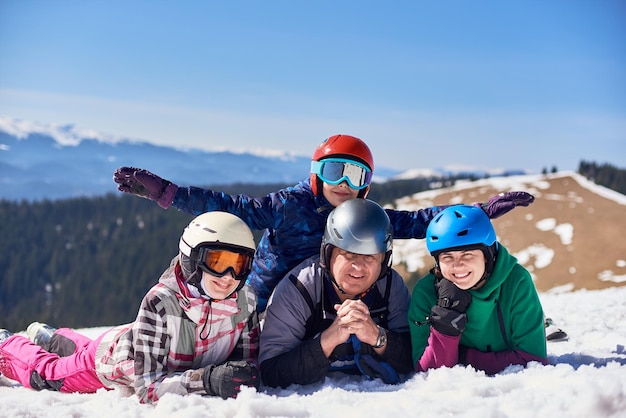 Famiglia sorridente felice su sci e snowboard nella neve profonda sullo sfondo delle montagne invernali