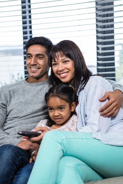 Famiglia sorridente guardando la tv sul divano