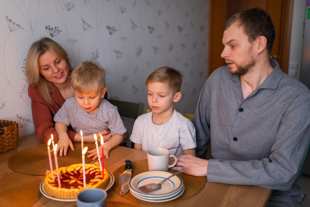 Famiglia sorridente mentre brucia candele sulla torta durante la festa di compleanno a casa