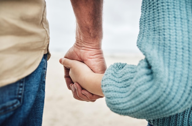 Famiglia spiaggia e padre che si tengono per mano con il bambino a sostegno della cura dei bambini fiducia e amore mentre si gode la pace libertà o legame Viaggio nel tempo di qualità e giovane ragazza e papà si rilassano insieme sulla sabbia calma