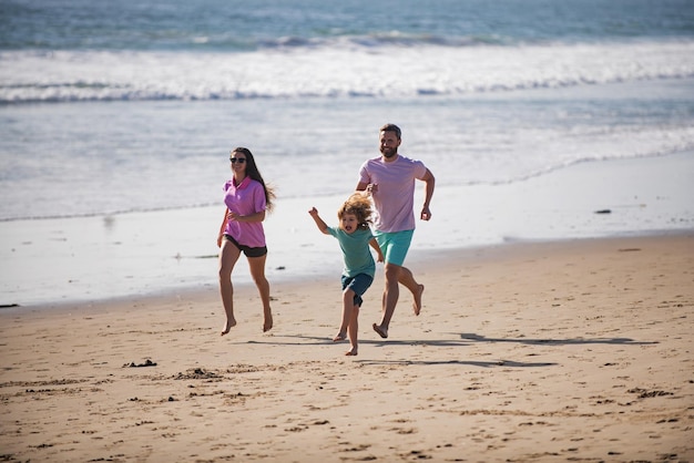 Famiglia sportiva che corre fuori l'acqua durante le vacanze estive in spiaggia e una famiglia sana e sportiva