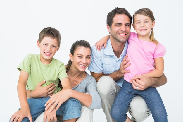 Famiglia sveglia che posa e che sorride insieme alla macchina fotografica