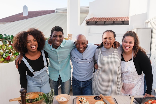 Famiglia unita che cucina cibo sano sulla terrazza della loro casa e condivide momenti Concetto stile di vita familiare cibo sano