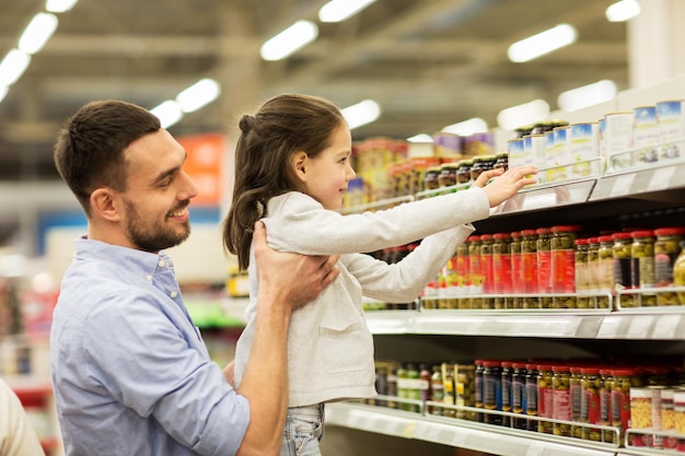 famiglia, vendita, shopping, consumismo e concetto di persone - padre felice con figlio che compra cibo al negozio di alimentari