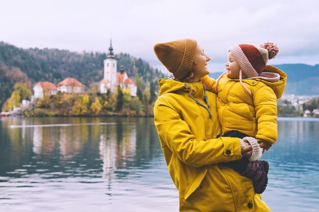 Famiglia Viaggi Europa Madre e bambino in impermeabili gialli guardando il lago di Bled Slovenia