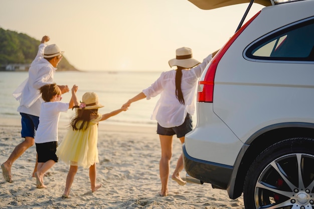 Famiglia, viaggi, spiaggia, relax, stile di vita, concetto di vacanza. Famiglia che gode di un picnic. I genitori tengono per mano i loro figli e camminano sulla spiaggia al tramonto in vacanza.