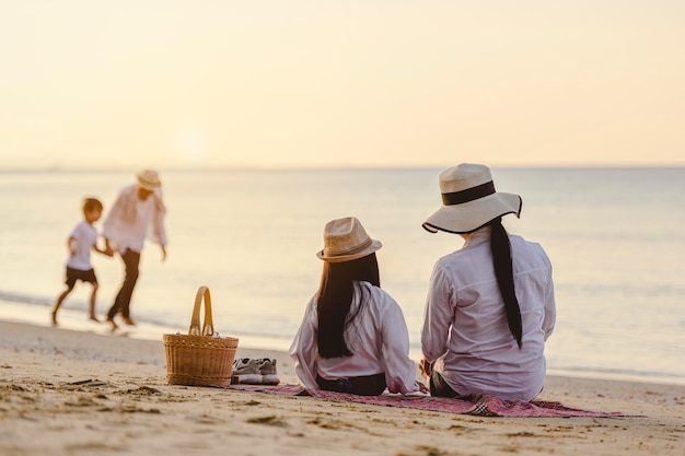 Famiglia, viaggi, spiaggia, relax, stile di vita, concetto di vacanza. Genitori e figli che in vacanza si godono un picnic in spiaggia al tramonto.