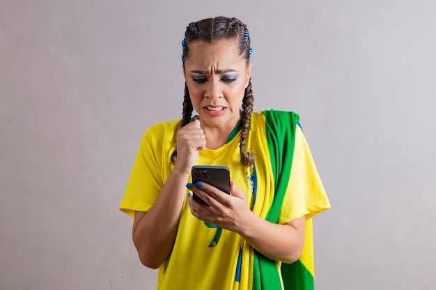 Fan brasiliana angosciata che guarda la partita del Brasile sul suo cellulare