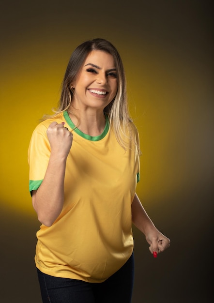 Fan brasiliana Fan brasiliana che festeggia in una partita di calcio o di calcio su sfondo giallo Colori del Brasile