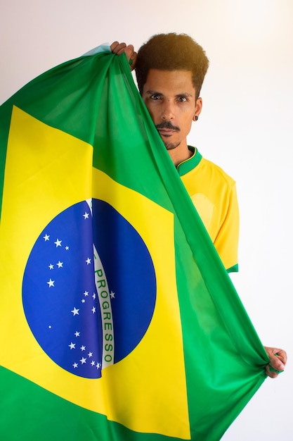 Fan brasiliano dell'uomo di colore con la maglia della squadra di calcio isolata su bianco