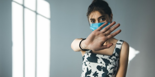 Fanale di arresto della mano della maschera di protezione della donna su gray