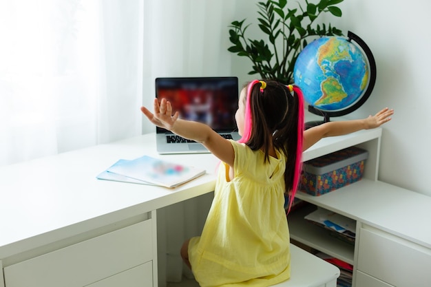 Fantastica scuola online. Bambino che studia online a casa usando un laptop. Allegra giovane bambina che utilizza il computer portatile che studia tramite il sistema di e-learning online. Formazione a distanza o a distanza