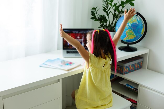 Fantastica scuola online. Bambino che studia online a casa usando un laptop. Allegra giovane bambina che utilizza il computer portatile che studia tramite il sistema di e-learning online. Formazione a distanza o a distanza