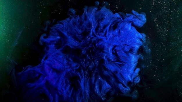 Fantastica vista di inchiostri colorati in movimento caotico su sfondo nero con particelle incandescenti