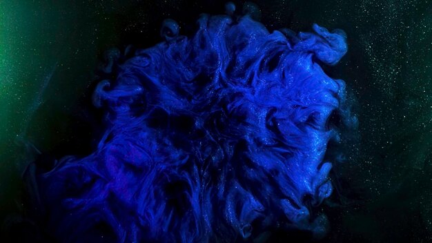 Fantastica vista di inchiostri colorati in movimento caotico su sfondo nero con particelle luminose