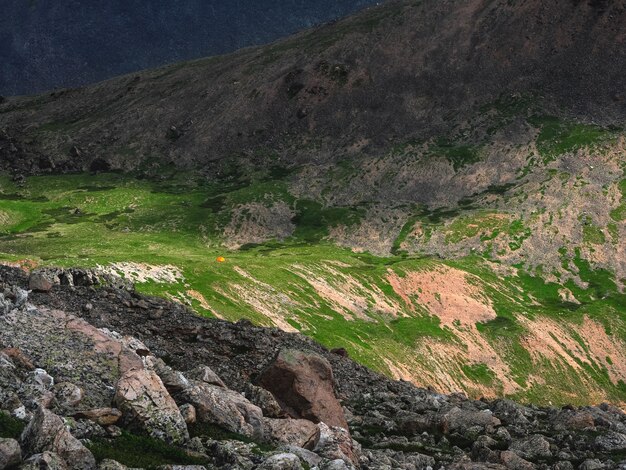 Fantastico paesaggio minimalista contrastante con i monti Altai e una piccola tenda sul pendio verde di una gola di montagna. Cresta Kurai.