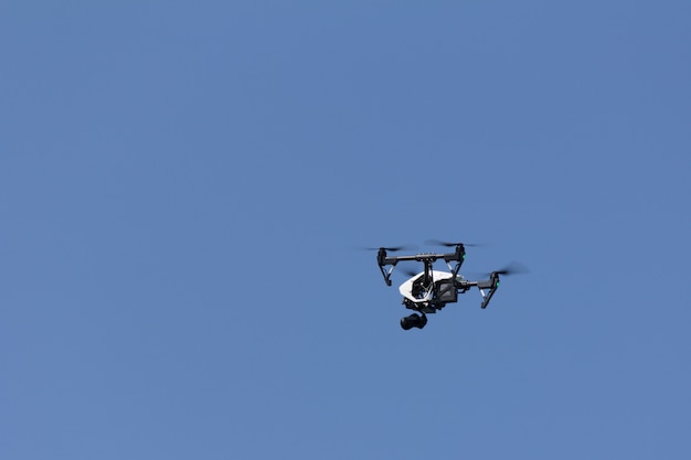 Far volare un quadricoptero sta filmando contro il cielo blu chiaro