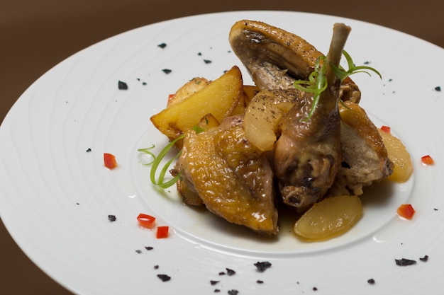 Faraona arrosto con patate, con erbe verdi, posta su un piatto bianco