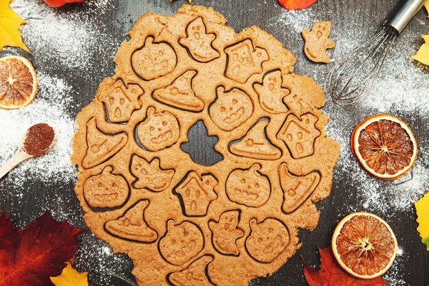 Fare i biscotti di pan di zenzero fatti in casa. Simboli di Halloween - zucca, cappello, fantasma. Sfondo di cibo autunnale.